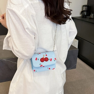 Borsa a tracolla azzurra con stampa ciliegie e fibbia in strass indossata da modella
