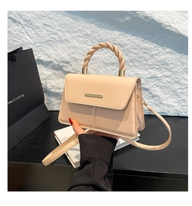 Détail d'un sac à main beige avec poignée torsadée et fermoir en métal doré élégant