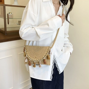 Boho chic hand-woven crossbody saddle bag with colorful tassels on a female model