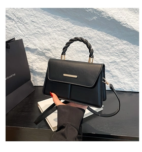Détail du sac à main trapèze noir avec poignée tressée et boucle métallique
