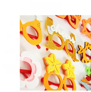 Close-up of vibrant felt party glasses with Cheers champagne and floral decorations
