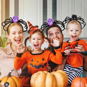 Family wearing plush spider headbands and pumpkin shirts in a festive Halloween kitchen setting