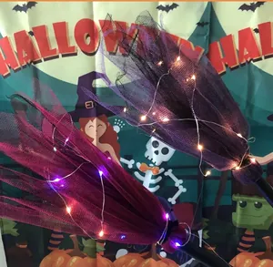 Détail de balais de sorcière à LED avec tulle violet et rose pour décor d'Halloween