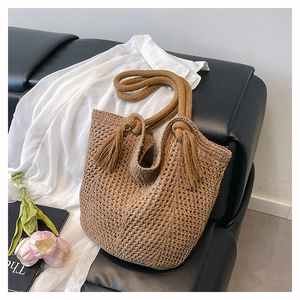 Detail of dark brown crochet tote bag with fringe accents and knit texture on sofa
