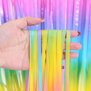 Détail d'un rideau à franges en aluminium arc-en-ciel dégradé tenu par une main