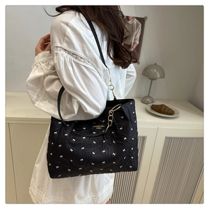 Détail du sac cabas plissé noir avec nœuds blancs et chaîne dorée sur mannequin