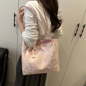 Pink lace tote bag with butterfly embroidery and tassel charm worn on shoulder