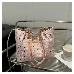 Détail du sac cabas rose avec broderie de nœuds noirs et chaîne dorée sur chariot argent