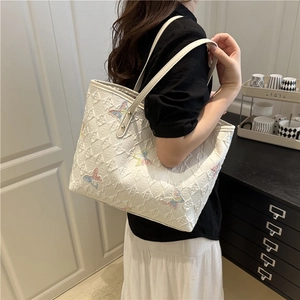 White quilted tote bag with butterfly embroidery and monogram pattern on a shoulder strap
