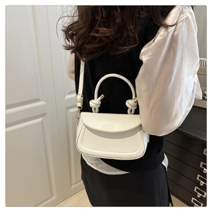 Model view of white leather crossbody bag with creative knot handle and saddle shape