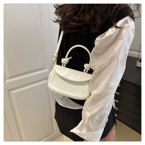 Detail of white mini crossbody bag with unique double knot handle and flap closure