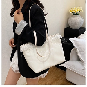 Close-up of a white denim tote bag with delicate lace trim and EVEA GLOW branding