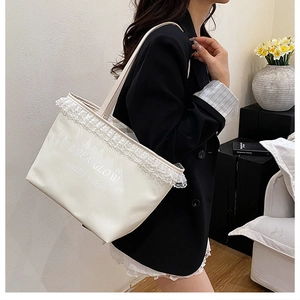 Detail of white leather tote bag with lace trim and elegant letter printing