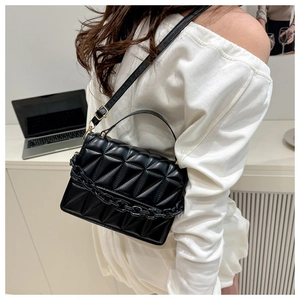 Détail du sac bandoulière noir matelassé avec chaîne décorative et boucles dorées