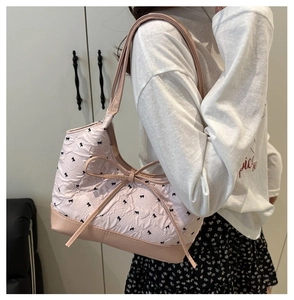 Détail du sac à bandoulière rose avec motifs de nœuds noirs et grand nœud central