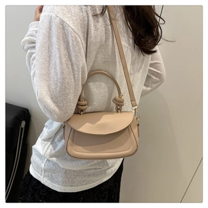 Detail of knot handle and adjustable strap on a minimalist beige leather crossbody bag