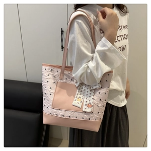 Detailed texture of pink quilted tote bag with rabbit patterns and decorative bow charm
