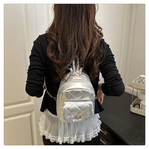 Detail showing the silver quilted mini backpack with chain strap and metallic lock