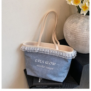Detailed close-up of a blue canvas tote bag with white lace trim and EVEA GLOW text