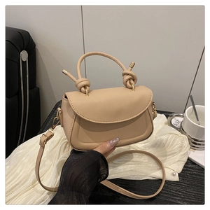 Detail of trendy beige crossbody bag with stylish knotted handle and adjustable strap