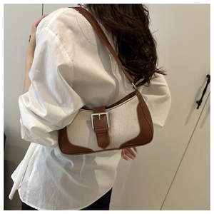 Detailed view of two-tone brown leather and beige canvas stitching on baguette shoulder bag