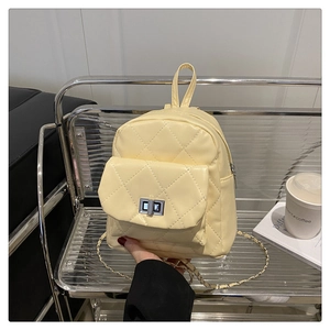 Close-up of yellow quilted mini backpack featuring silver twist lock and chain strap detail
