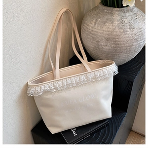 Close-up of cream tote bag featuring elegant white lace edges and Evea Glow print