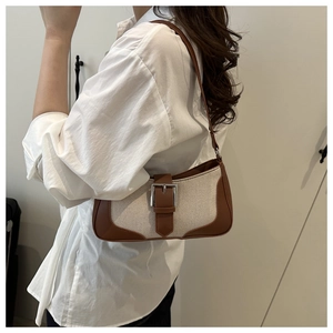 Detail view of a vintage brown leather and beige canvas baguette bag styled on a model