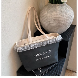 Detail of dark grey tote bag featuring white lace trim and minimalist printed logo text