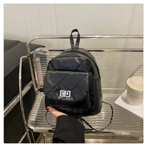 Detail of black quilted mini backpack with silver twist lock and woven chain strap