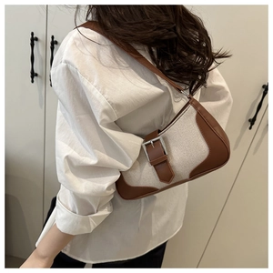 Detail of trendy baguette bag in beige canvas and brown leather on model's shoulder
