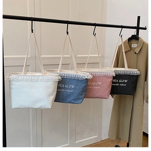Close-up of four canvas tote bags with lace trim and elegant lettering in various colors