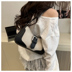 Detail of canvas shoulder bag with black leather trim and silver metal buckle on a model