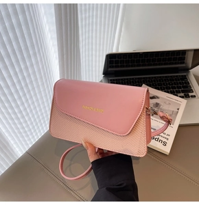 Detail of pink fashion bag with gold lettering on a minimalist desk setup