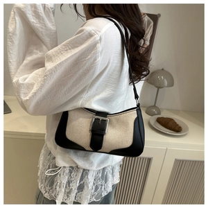 Close-up of contrast canvas shoulder bag with black leather trim and silver buckle