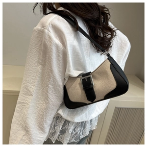 Detail view of the beige canvas baguette bag with black leather trim and silver buckle