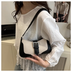 Detail of canvas baguette bag with black leather trim and silver metal buckle accent