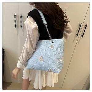 Detail of light blue tote bag featuring colorful sequin butterfly embroidery and metal chains
