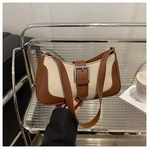 Close-up of canvas baguette bag with leather stitching and vintage metal buckle