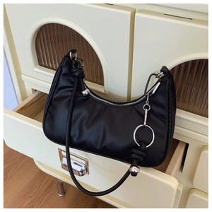 Close-up of black leather crescent bag with silver zipper and decorative metal ball detail