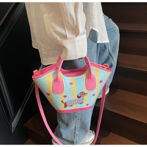 Détail du sac seau teckel avec anses roses porté par un mannequin sur des escaliers