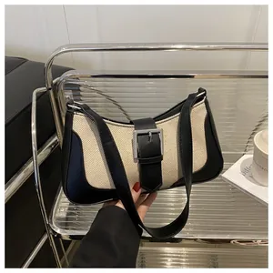 Detailed view of canvas and leather contrast handbag with silver buckle and black strap