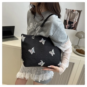 Close-up of black quilted tote bag featuring colorful sequin butterfly embroidery and chain