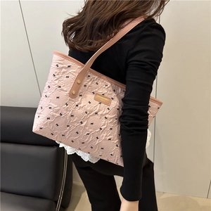 Pink pleated tote bag with black bow print and brown faux leather straps worn by model