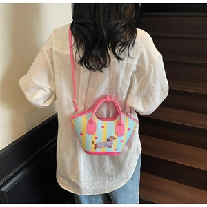 Détail du sac seau teckel avec motif rayé et bandoulière rose sur un mannequin