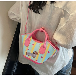 Détail du sac seau teckel avec rayures bleues et motifs d'étoiles roses porté par le mannequin