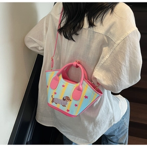 Détail du sac seau teckel avec rayures bleu-jaune et bandoulière rose sur un mannequin