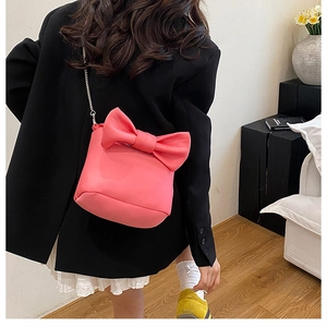 Pink bow bucket bag with silver chain strap shown over a black blazer for a sweet style