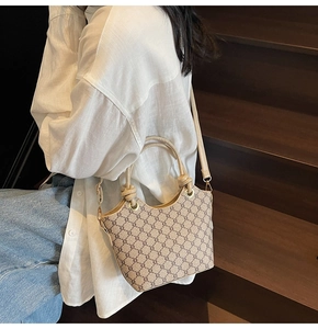 Détail du sac seau vintage avec motif monogramme et anse en cuir à nœud design
