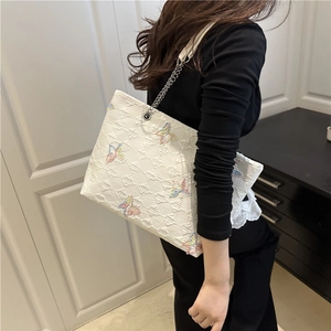 White quilted tote bag with colorful butterfly embroidery and silver chain strap